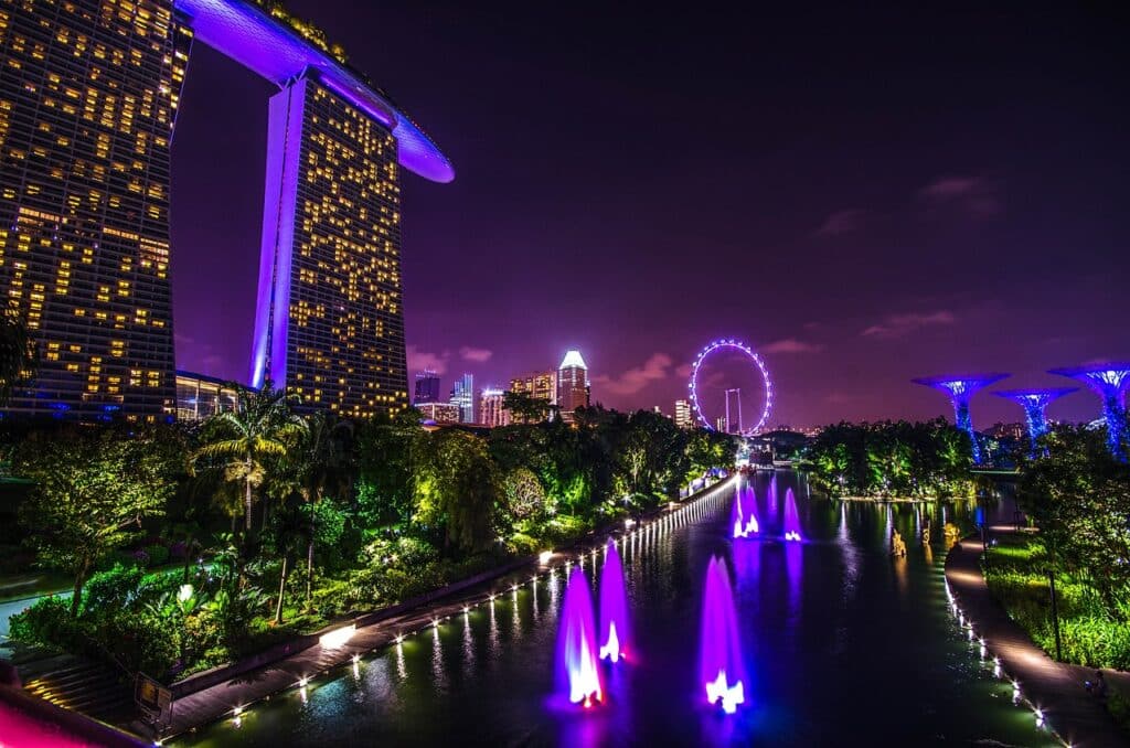 a water fountain with purple lights and buildings in the background