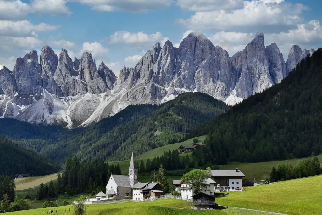 a group of houses in a valley with mountains in the background with Dolomites in the background
